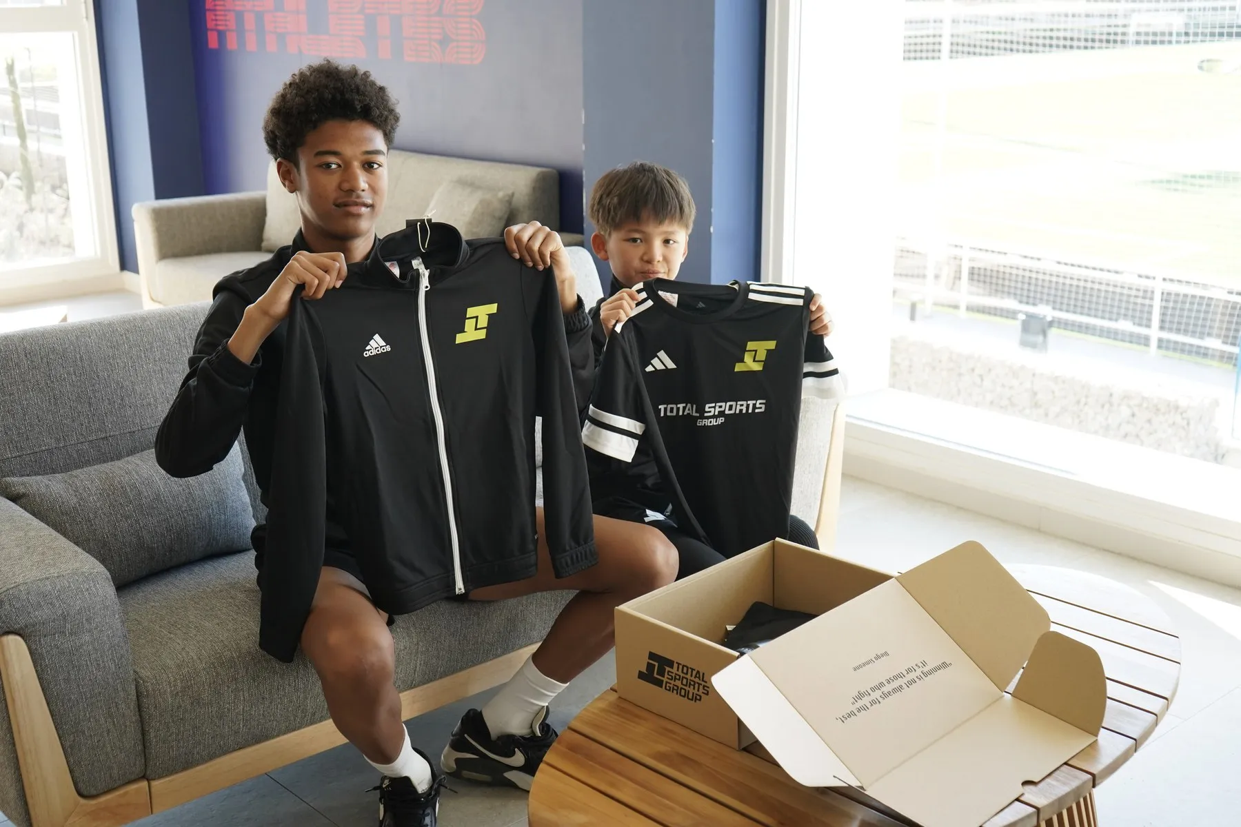 Dos alumnos mostrando su equipación de Total Sports en la sala común de la residencia