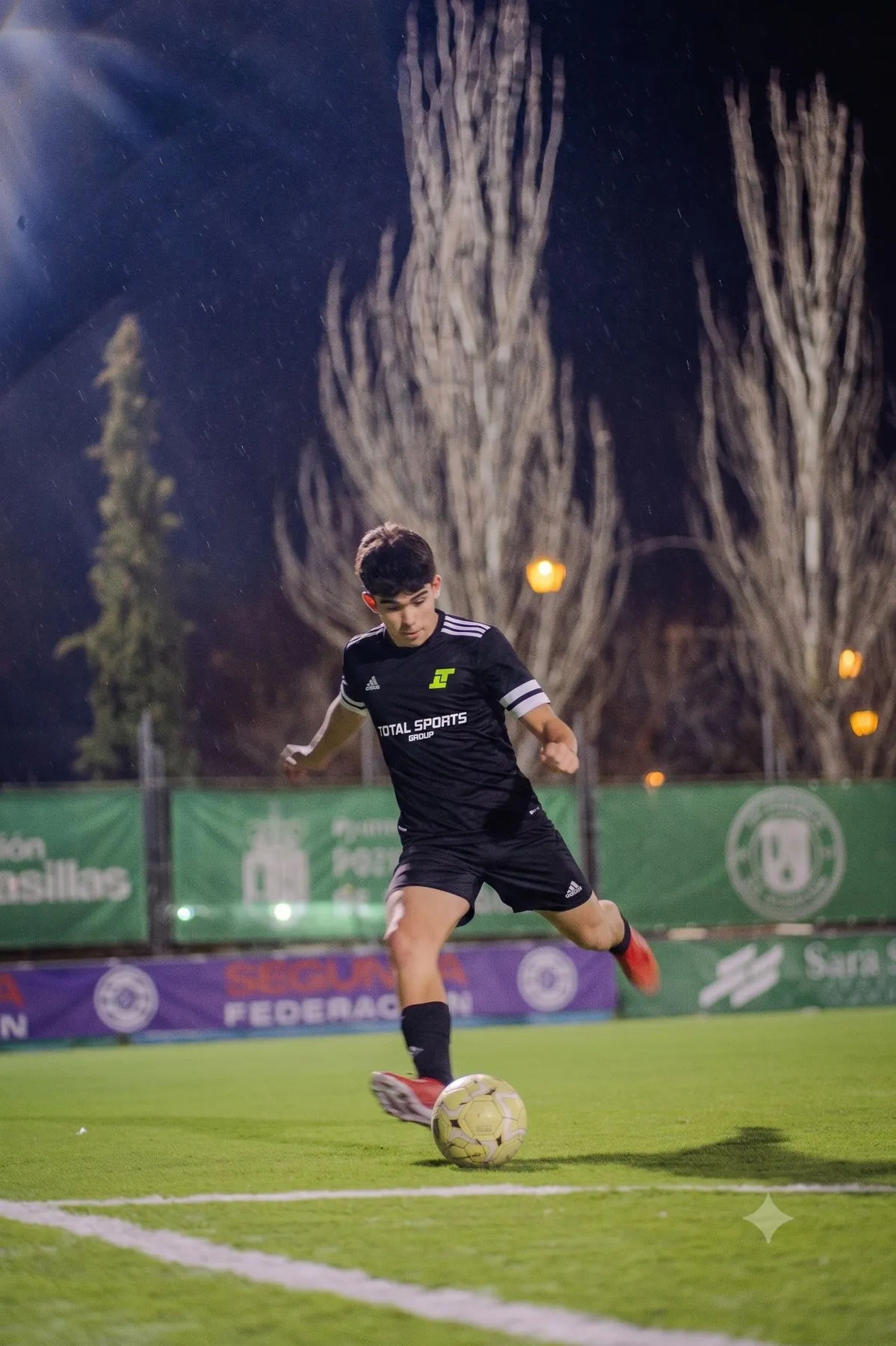 Un jugador golpeando el balón bajo los focos en un partido nocturno