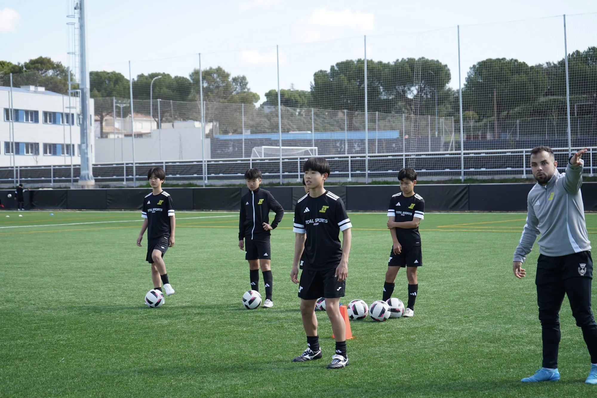 Un entrenador dando indicaciones a los jugadores alrededor del balón