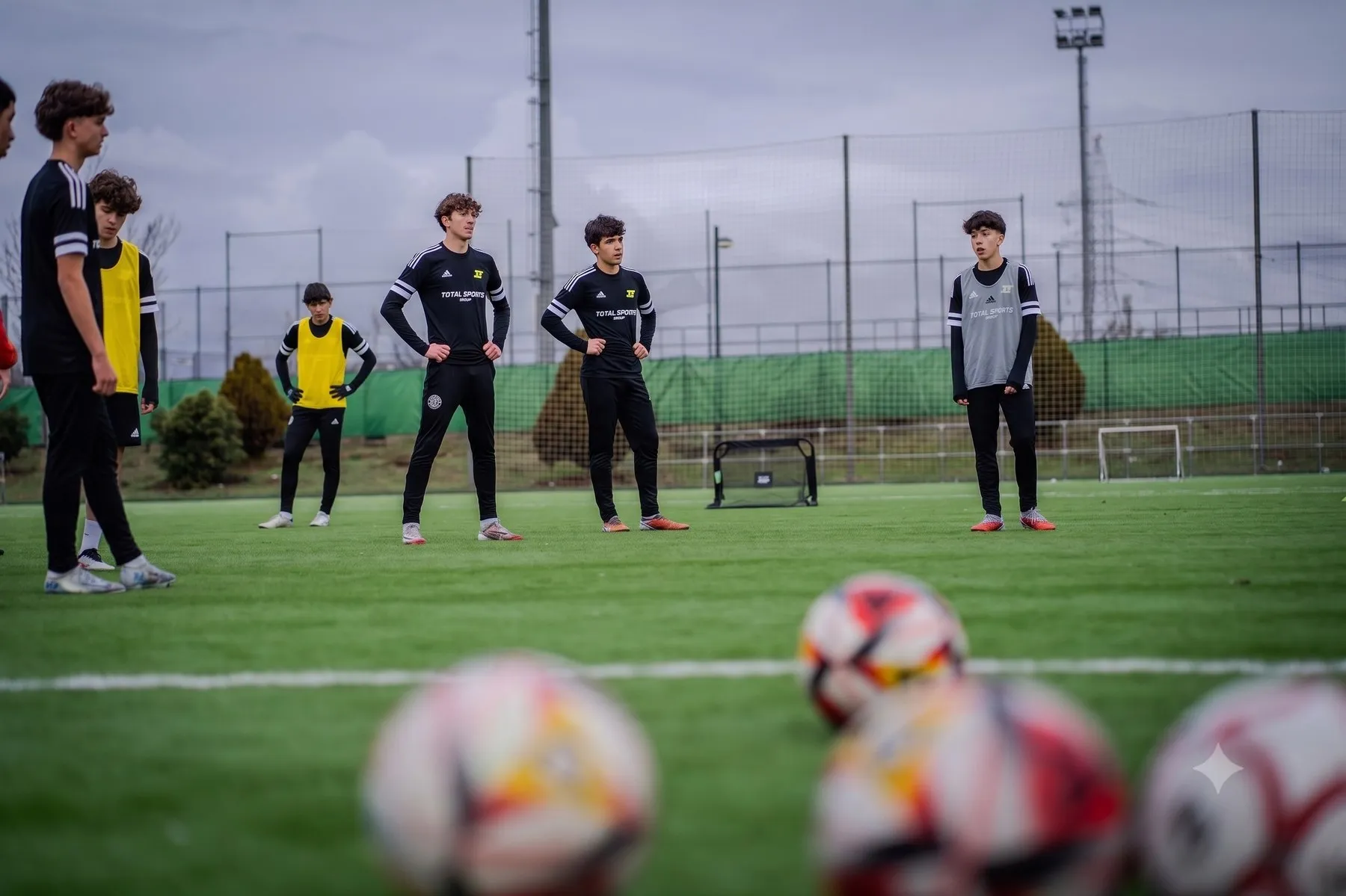 Jugadores atendiendo a las indicaciones en el campo, con balones en primer plano