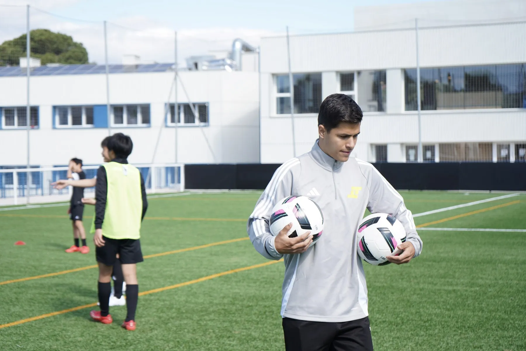 Un entrenador llevando balones al campo durante el entrenamiento