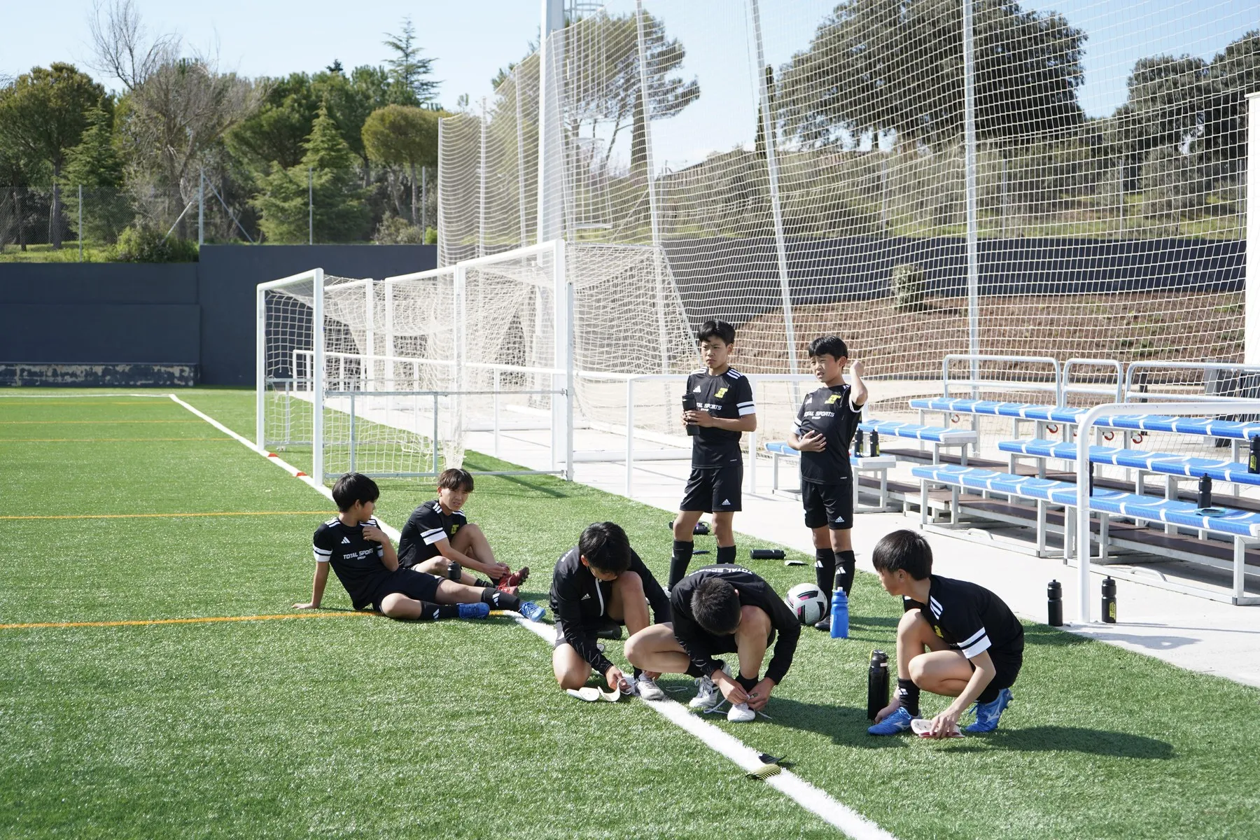 Jugadores descansando y cambiándose las botas al borde del campo del campus